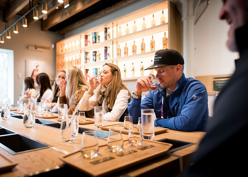 a table of people holding a smelling glasses of whisky at a tasting event