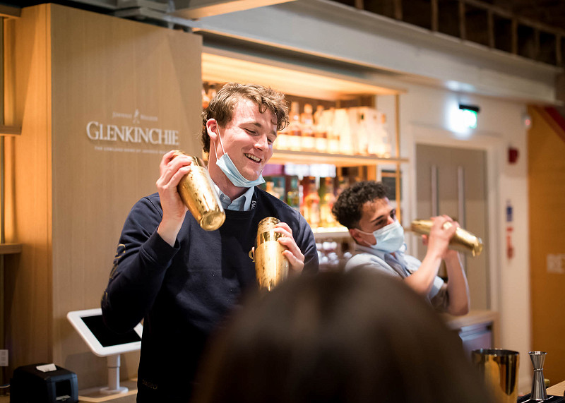 A bartender shakes a cocktail shaker in the bar at a whisky distillery visitor centre