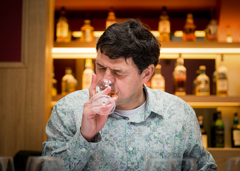 A man closes his eyes and has a look of concentration as he sniffs a glass of whisky at a whisky judging event