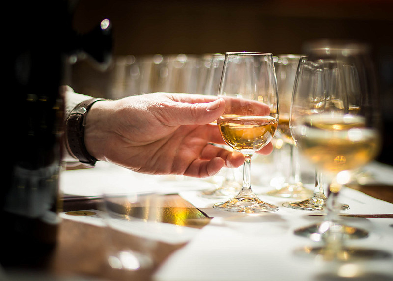 A hand reaches for one of several glasses of whisky at a whisky judging event