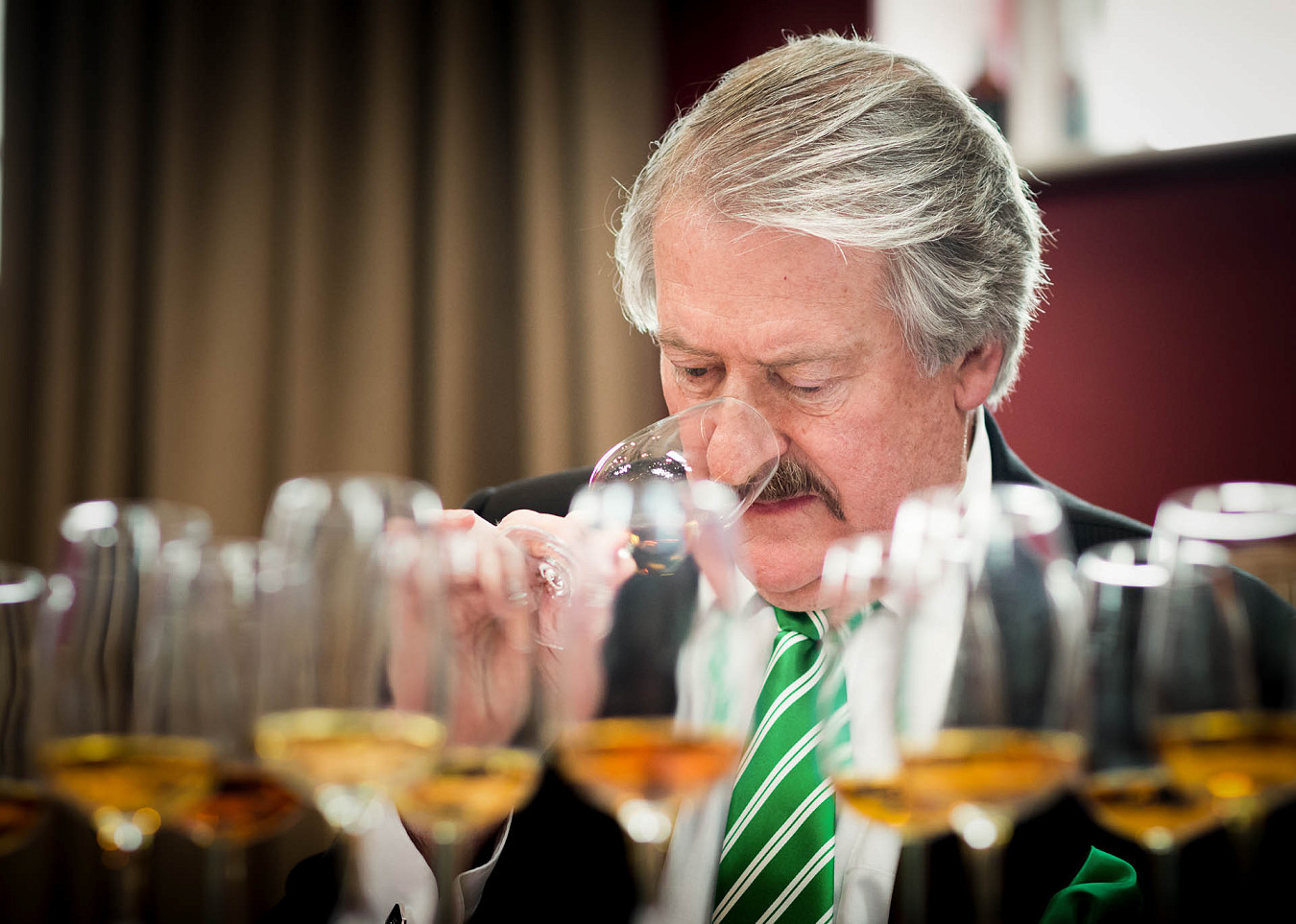 Master blender RIchard Paterson sniffs one whisky from a flight of several glasses of whisky at a judging event