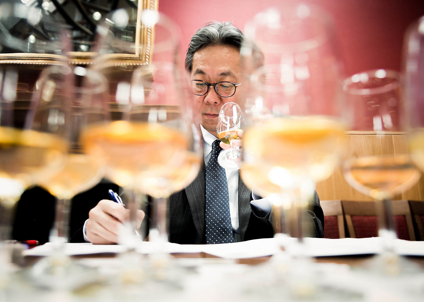 A man takes notes while holding and sampling a whisky at a judging event