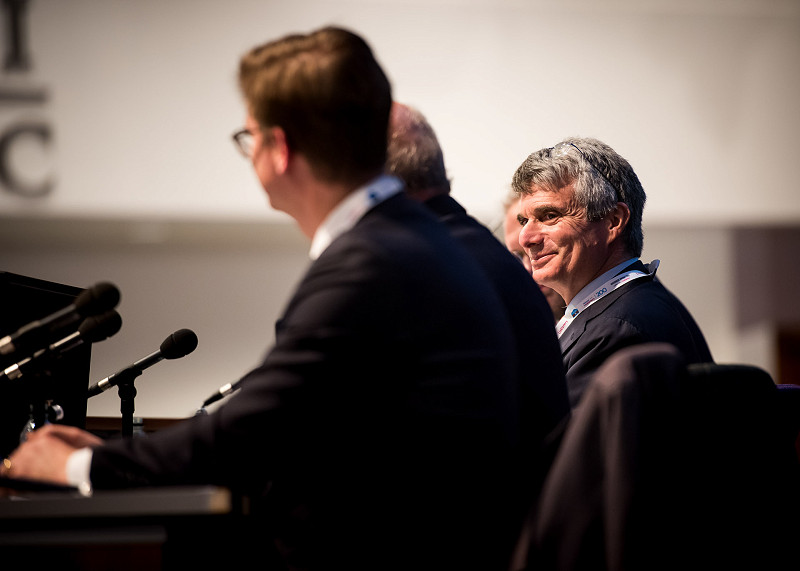Man smiling at fellow speaker while part of a discussion panel at a conference.