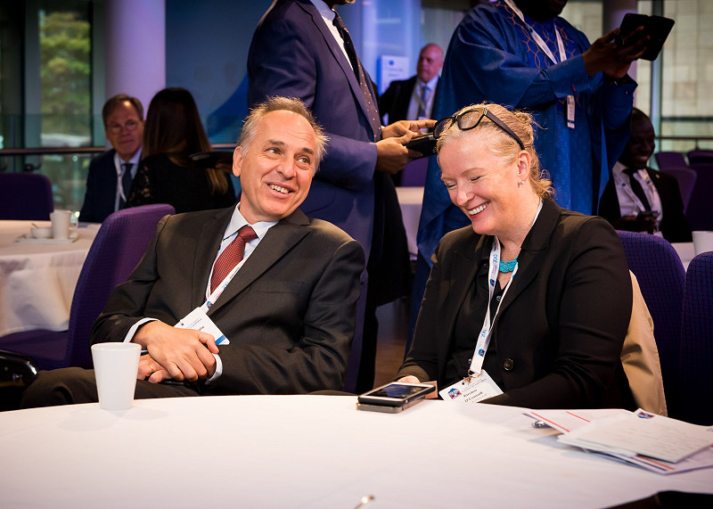 Man and woman laughing and smiling while talking at a conference