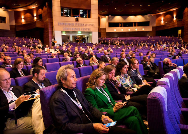 Wide angle photo of auditorium full of people at a business conference