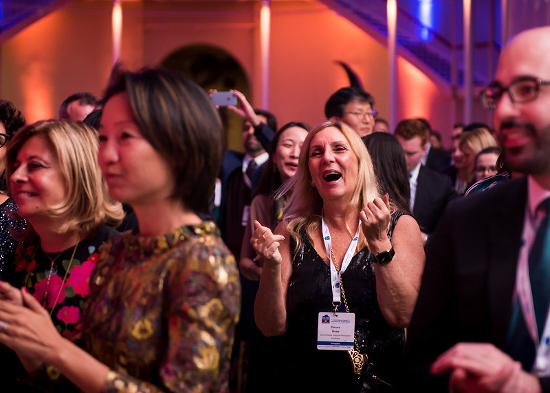 A woman cheers excitedly while watching live music at a conference evening event