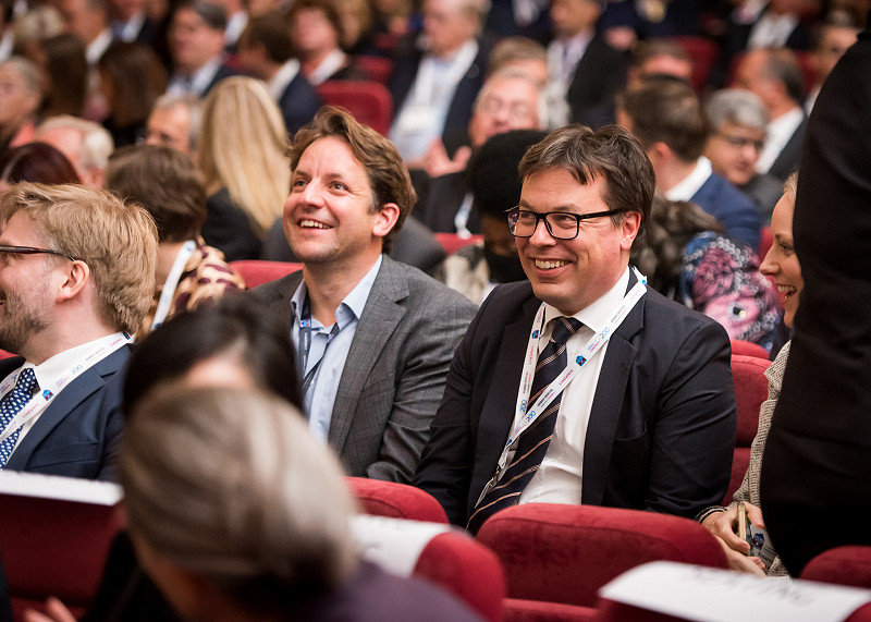 Two conference delegates laughing while sitting in an auditorium