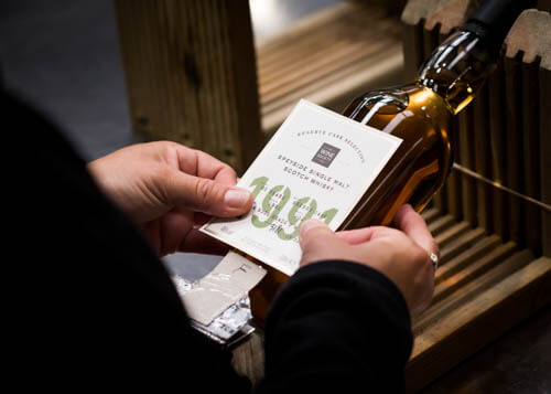 Whisky label being put onto a bottle whisky in the bottling plant